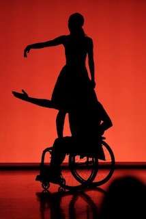 Silhouette von einer Person im Rollstuhl und einer weiteren Person